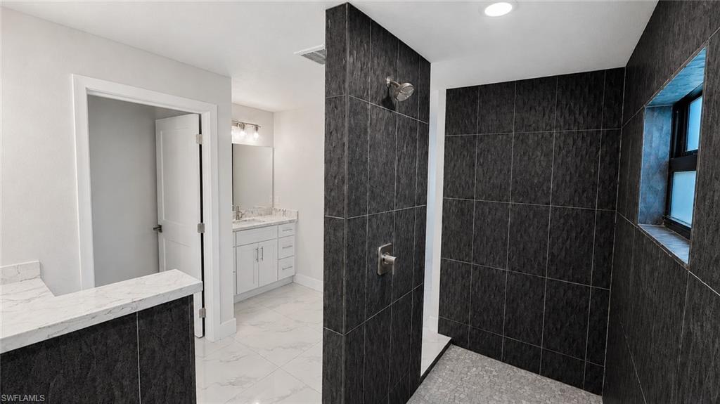 Spacious shower enclosure with dark textured tile walls and built-in window niche