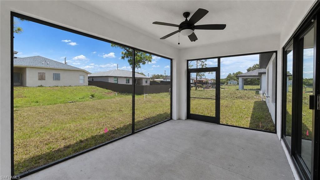 Screened outdoor living space featuring concrete flooring, a ceiling fan with integrated lighting, and multiple sliding glass door access points