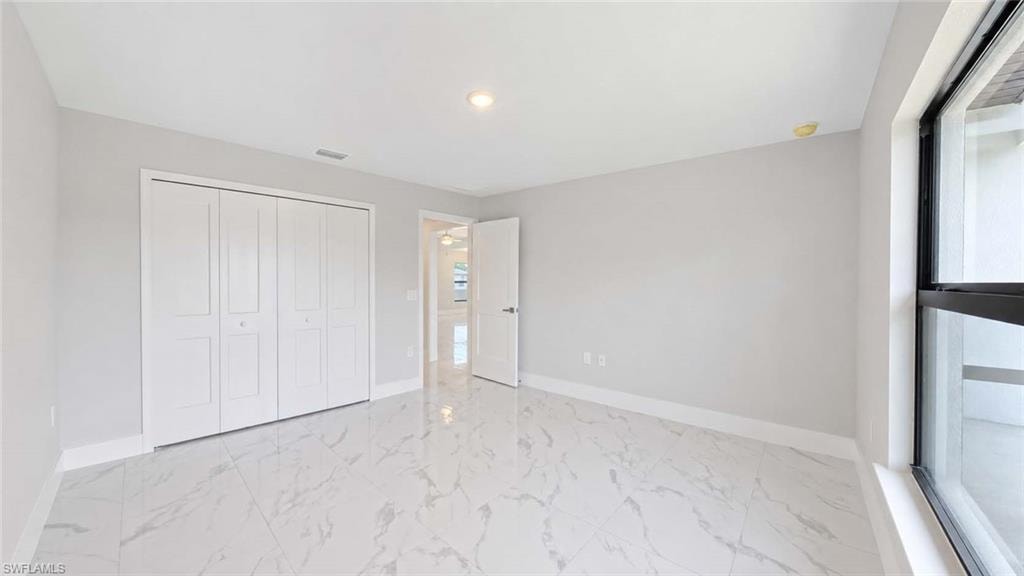 Room featuring large format marble-look tile flooring, white baseboards, and light gray painted walls