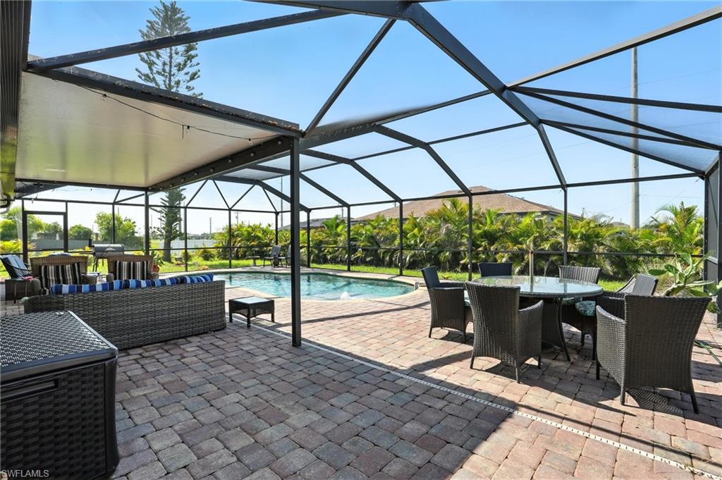 Screened outdoor living area featuring a paved brick patio, a built-in swimming pool, and a covered section with recessed lighting