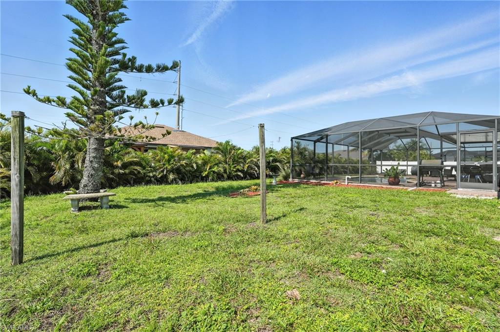 Expansive rear yard featuring a large screened enclosure, mature landscaping, and a concrete patio space