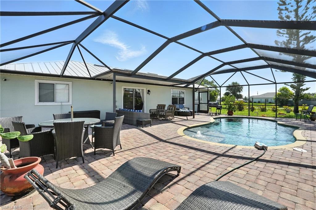 Screened lanai featuring a curved swimming pool, a paver patio, and a covered patio area