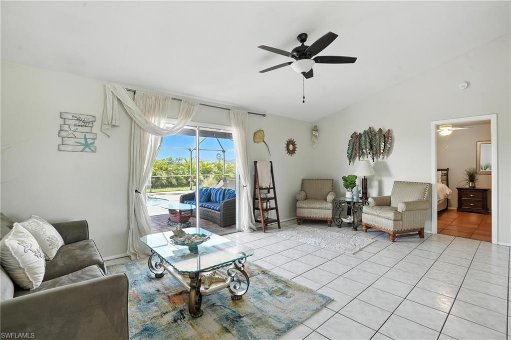 Spacious room featuring tile flooring, sliding glass doors to the exterior, a ceiling fan, and a doorway to an additional room