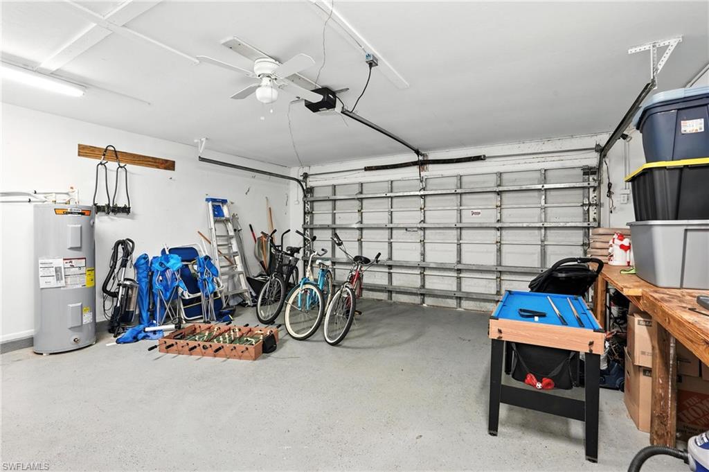 Garage featuring an automatic overhead door, epoxy-coated concrete flooring, a ceiling fan, and track lighting