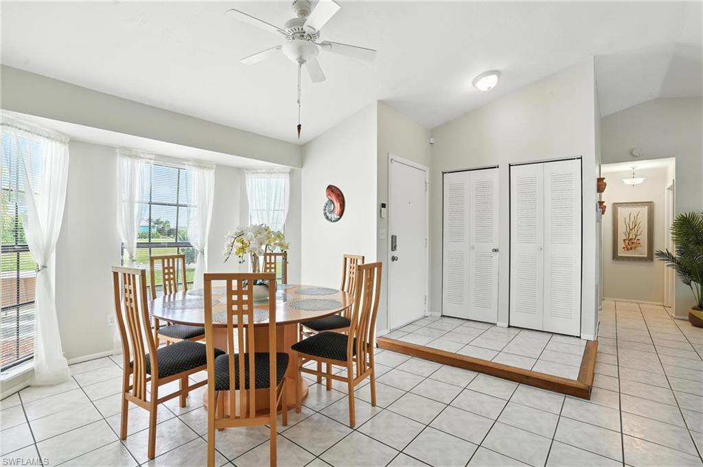 Dining area featuring a bay window, vaulted ceiling, and white tile flooring