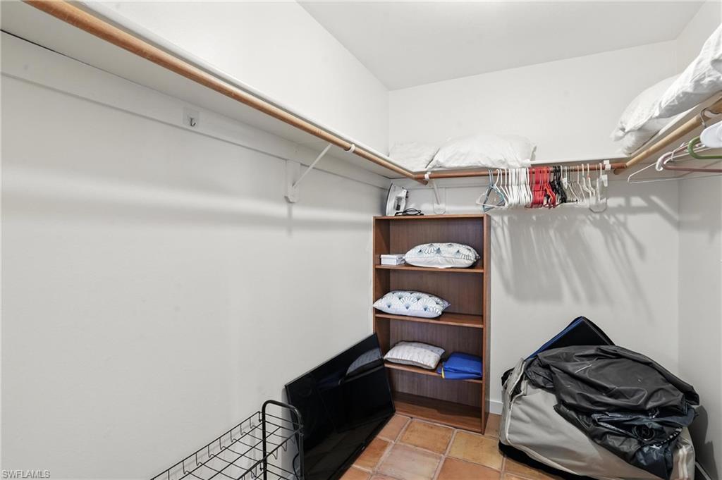 Walk-in closet featuring built-in shelving, wood rods, and tile flooring