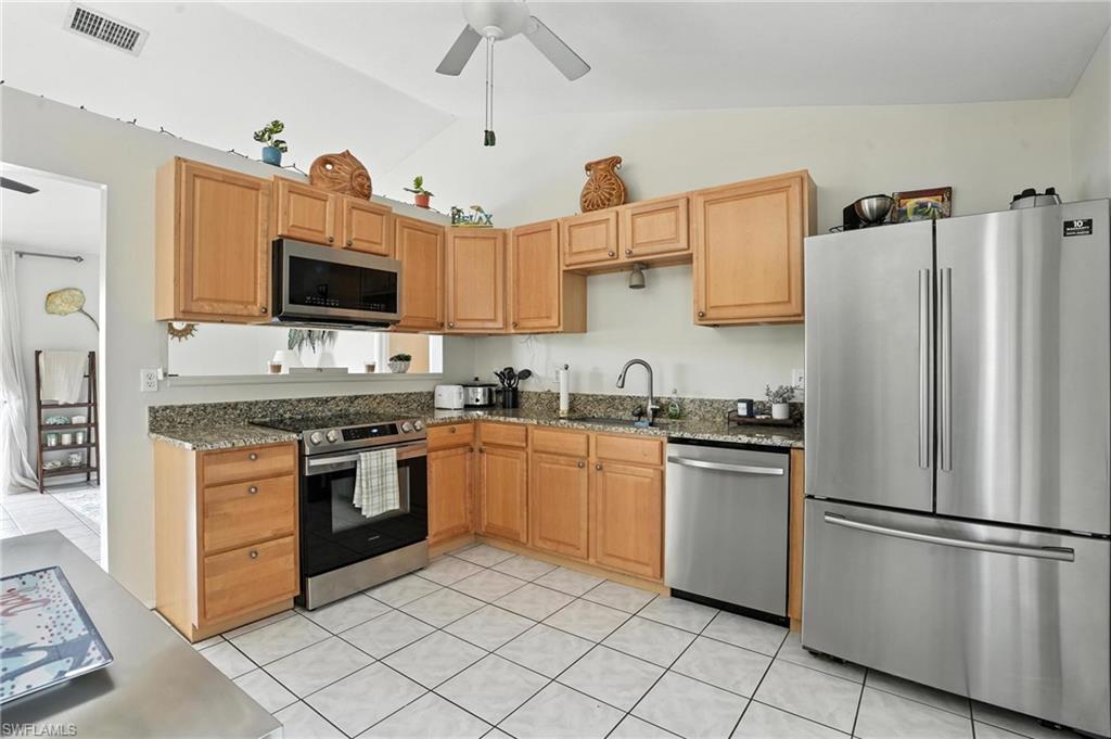 Kitchen featuring light wood cabinetry, granite countertops, and white tile flooring