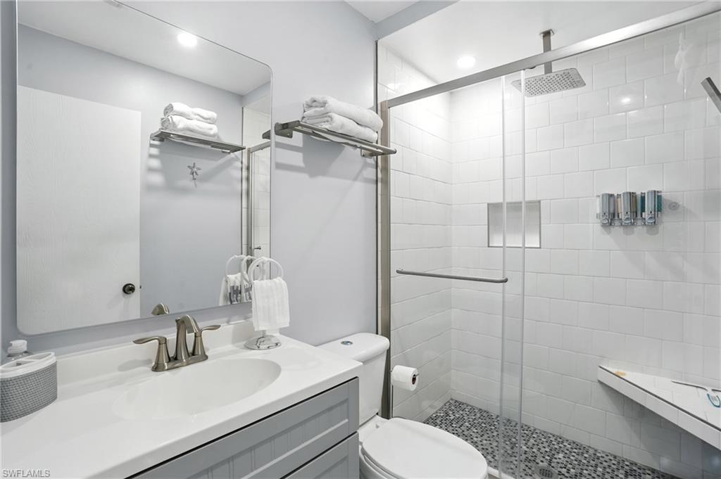 Contemporary bathroom featuring a spacious glass-enclosed shower with pebble flooring, a rain shower head, and a built-in shower niche