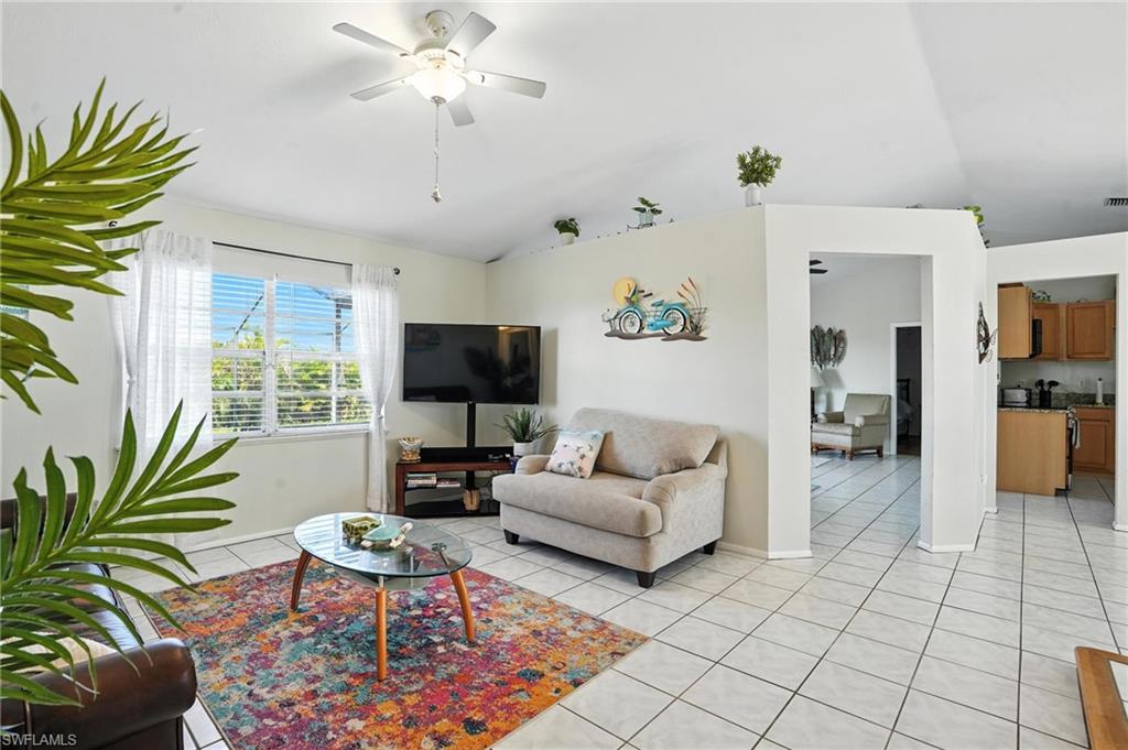 Spacious living area featuring vaulted ceilings, a ceiling fan with integrated lighting, and white tile flooring