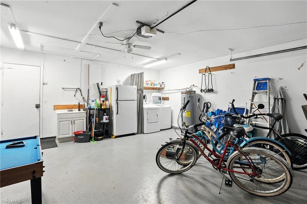 Spacious garage featuring a utility sink, a water heater, overhead fluorescent lighting, a ceiling fan, and a painted concrete floor
