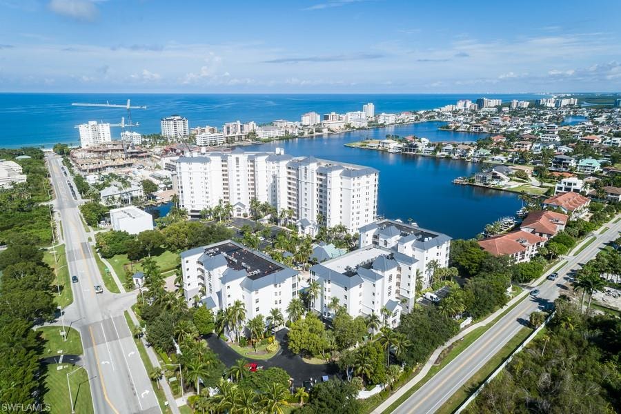 Aerial overview of property's location featuring a large body of water, apartment complex, and nearby urban area