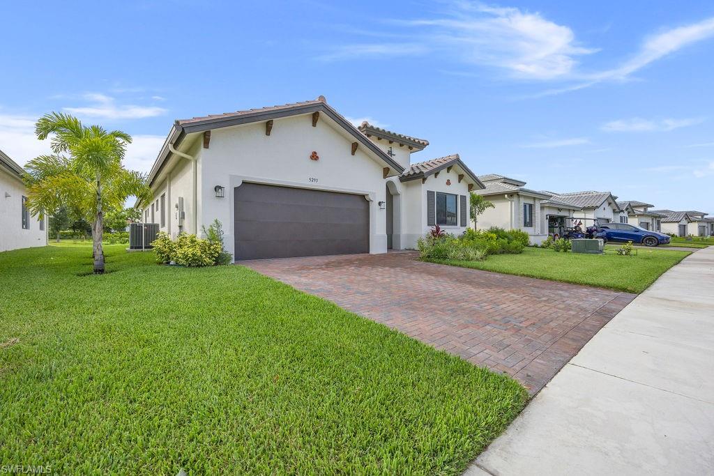 View of front of property featuring a front yard, a garage, and central AC