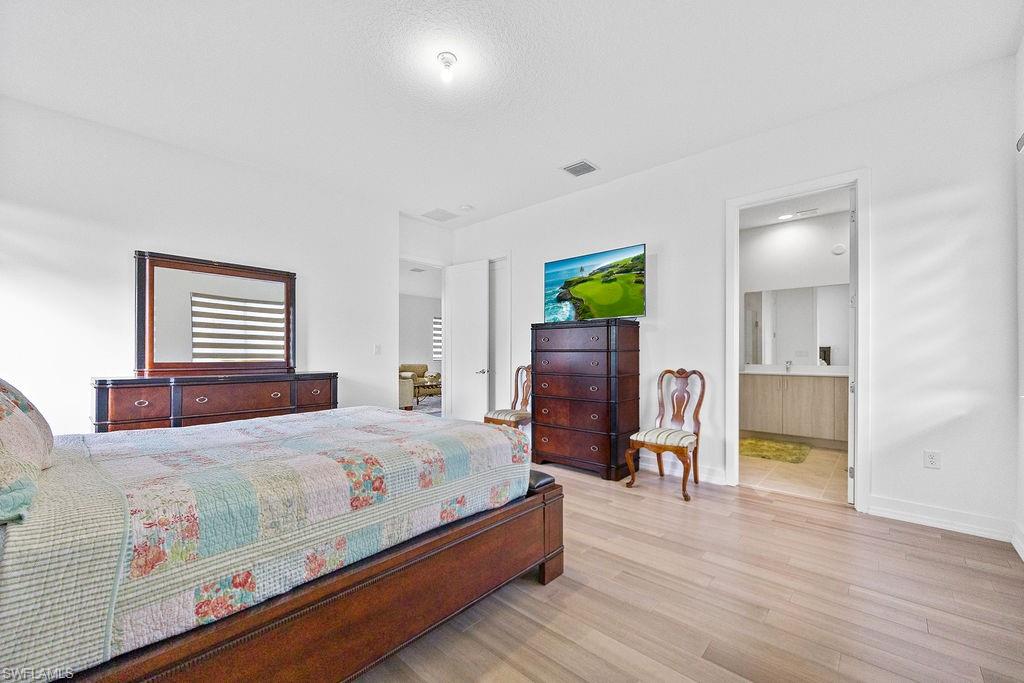 Bedroom with connected bathroom and hardwood / wood-style flooring
