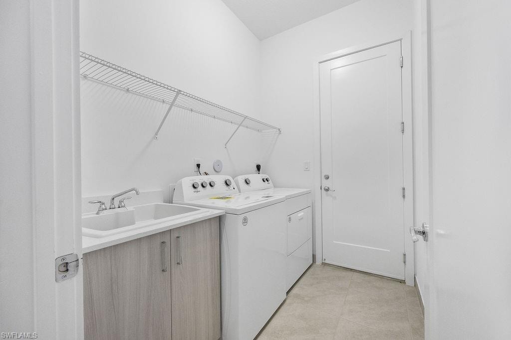 Laundry area with sink, hookup for an electric dryer, light tile floors, and washing machine and clothes dryer