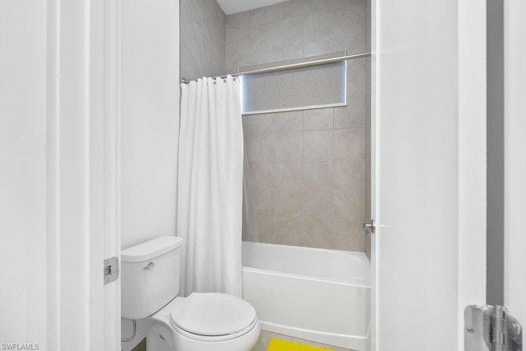 Bathroom with toilet and shower / bath combo with shower curtain