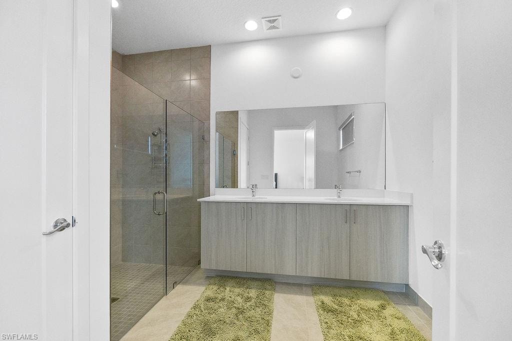 Bathroom with tile floors, walk in shower, oversized vanity, and dual sinks