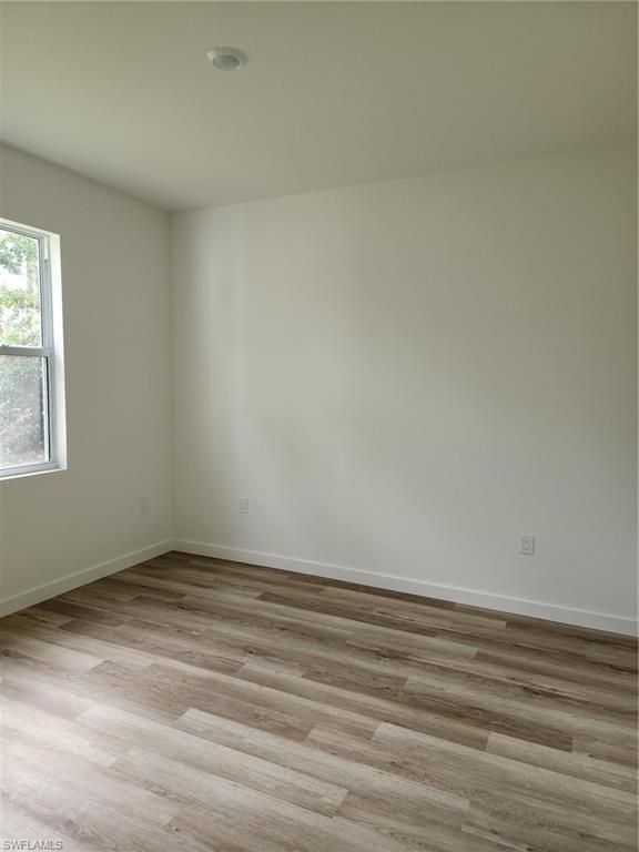 Unfurnished room with light wood finished floors and baseboards