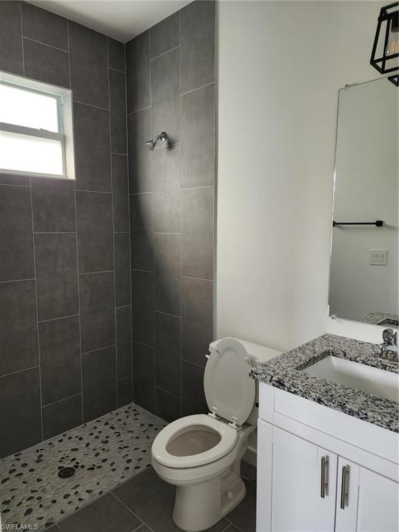 Bathroom with a stall shower, vanity, and dark tile patterned flooring