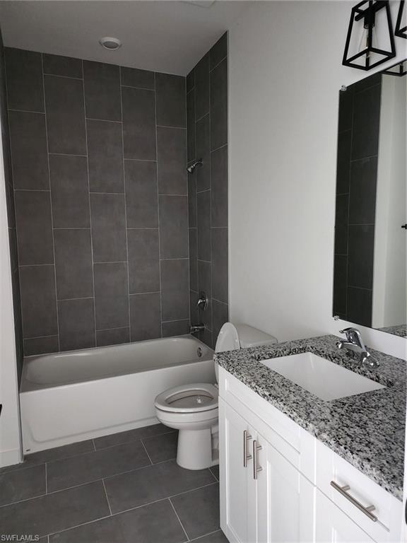 Full bathroom with vanity, bathing tub / shower combination, and dark tile patterned floors