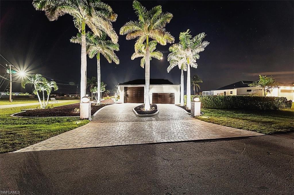 View of front of property with a garage, decorative driveway, and a yard