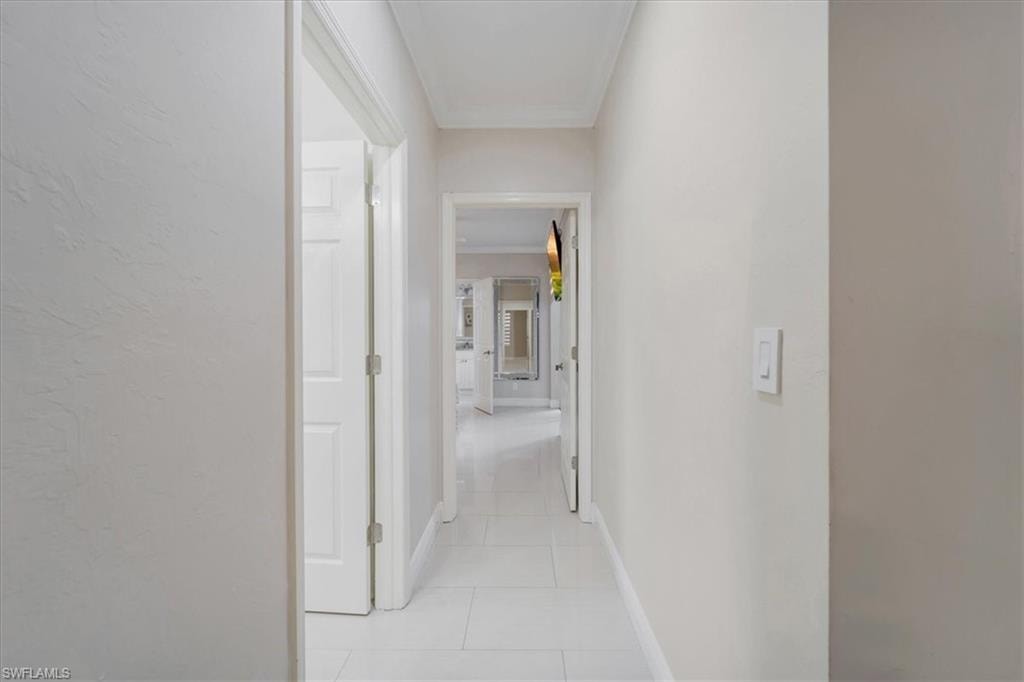 Hall with crown molding and light tile patterned floors