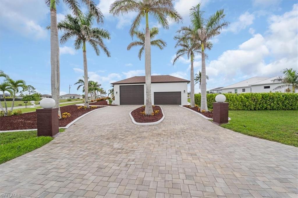 View of front of property with decorative driveway, a front lawn, and an attached garage