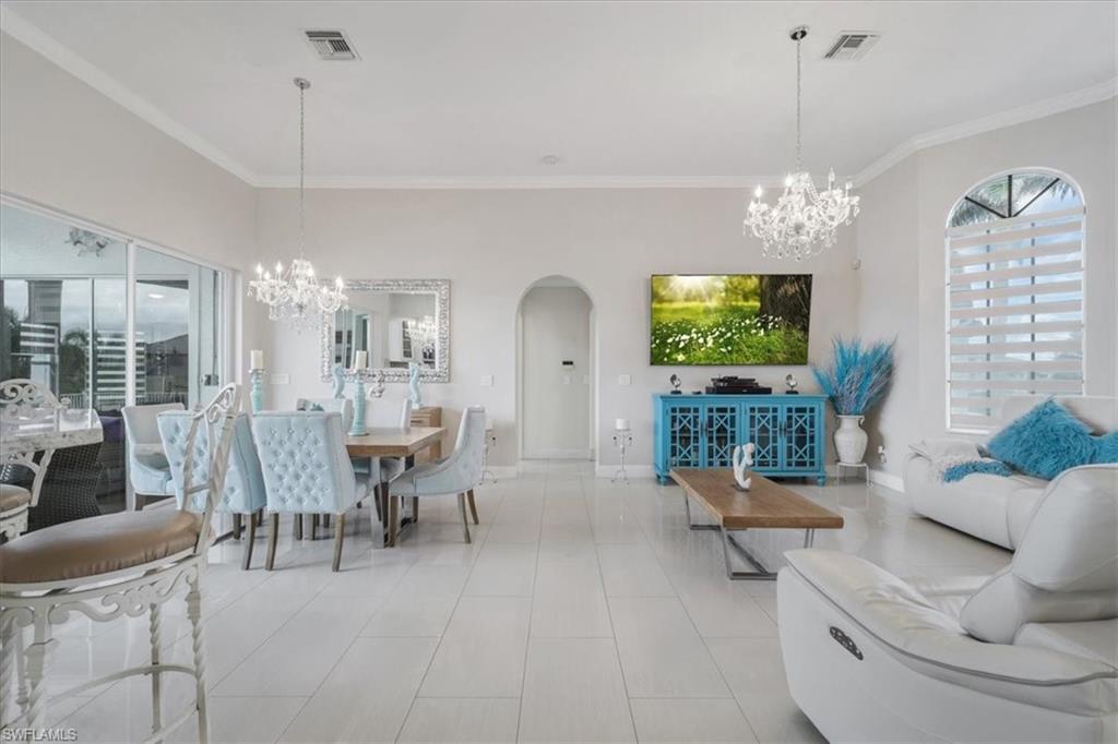Dining space featuring a chandelier, arched walkways, ornamental molding, and light tile patterned floors