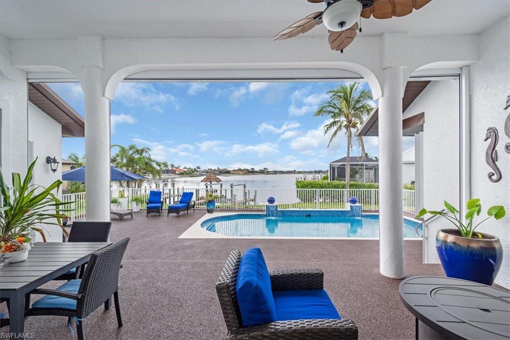 View of swimming pool with a fenced backyard, a patio, a water view, and a ceiling fan