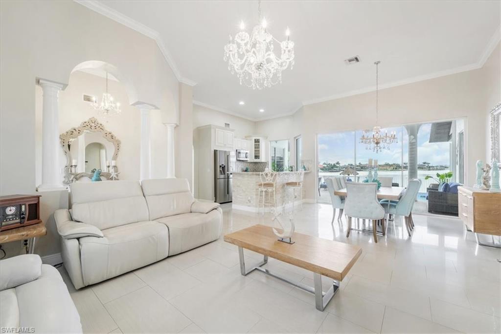 Living room featuring a chandelier, ornamental molding, light tile patterned floors, arched walkways, and recessed lighting