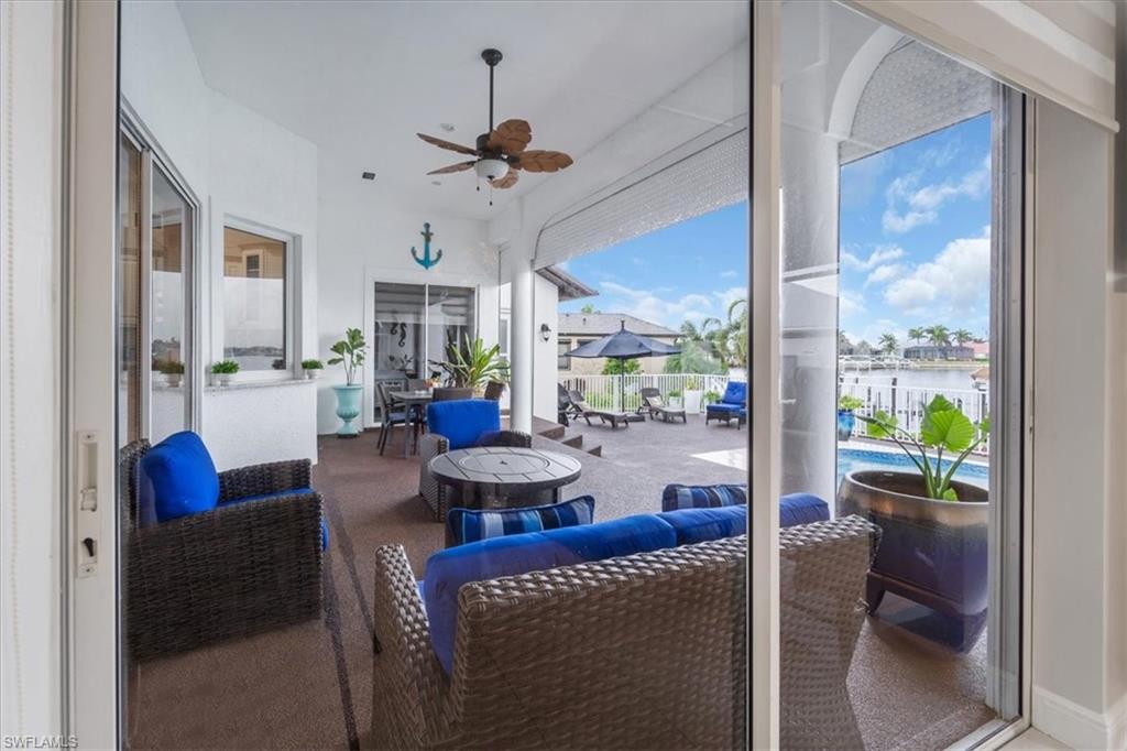 View of patio with a ceiling fan, an outdoor living space with a fire pit, and a water view