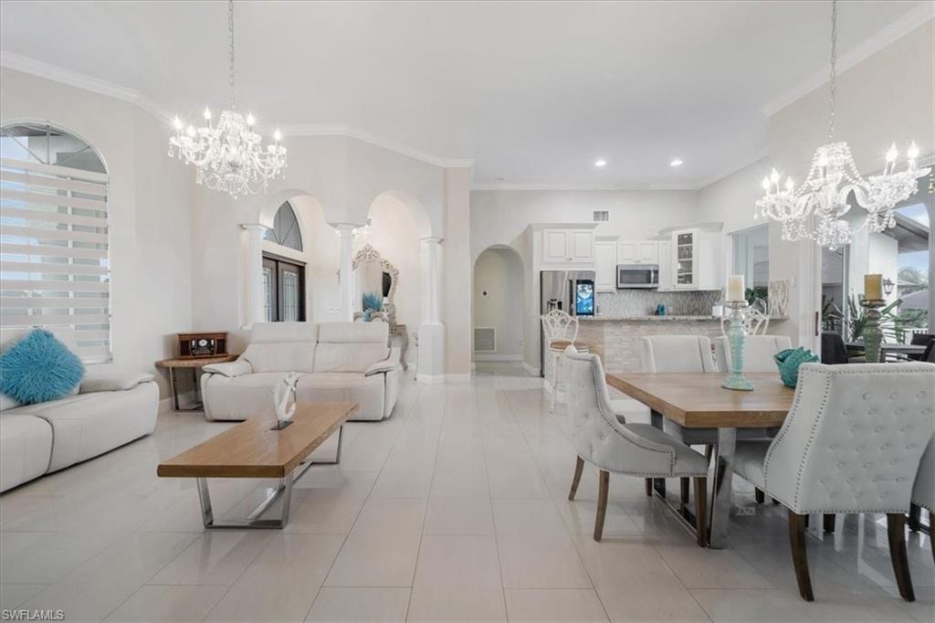 Dining area with a chandelier, arched walkways, crown molding, light tile patterned floors, and healthy amount of natural light
