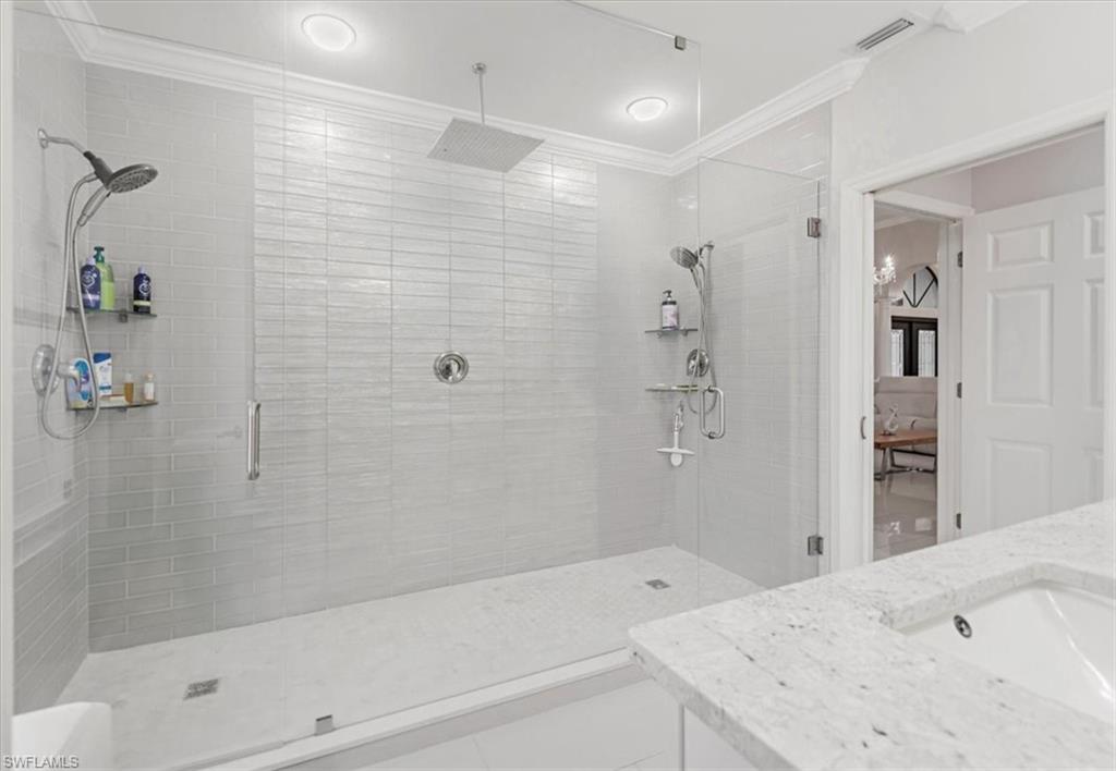 Bathroom with a shower stall, vanity, tile patterned flooring, and crown molding