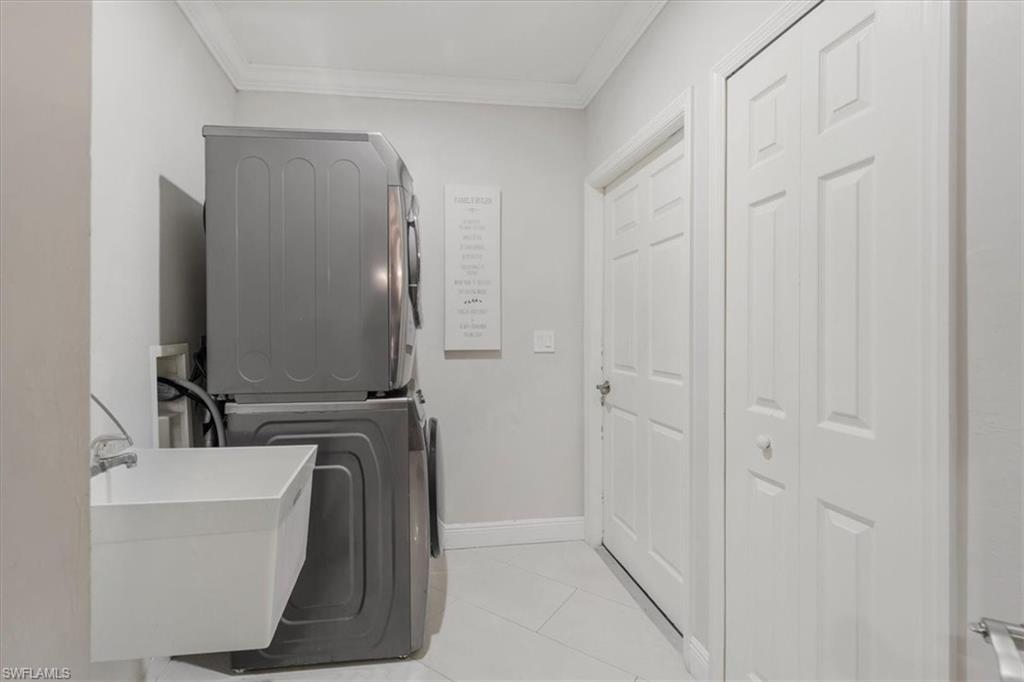 Laundry room featuring ornamental molding, stacked washer / drying machine, and light tile patterned flooring