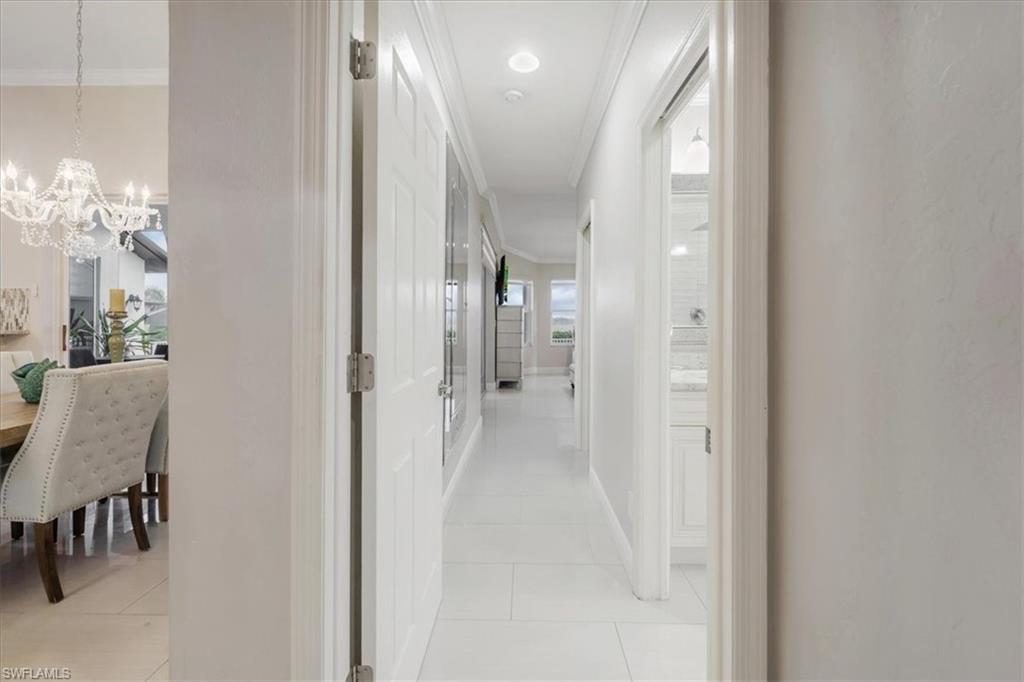Hall featuring crown molding, light tile patterned flooring, and a chandelier