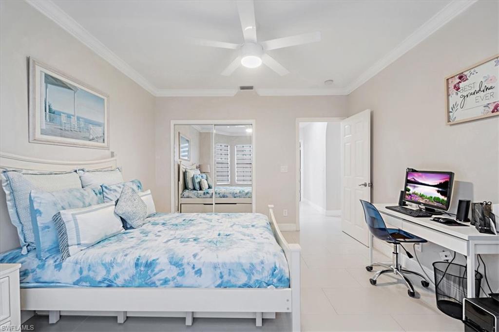 Bedroom with an office area, crown molding, a closet, ceiling fan, and light tile patterned flooring