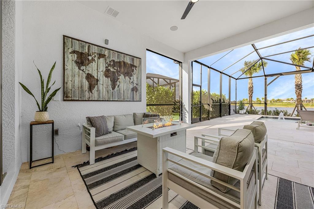View of patio / terrace featuring an outdoor living space with a fire pit, a sunroom, glass enclosure, ceiling fan, and a water view