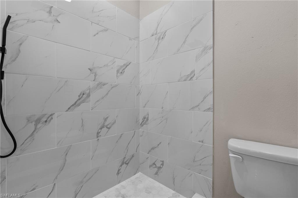 Full bath with tiled shower and toilet
