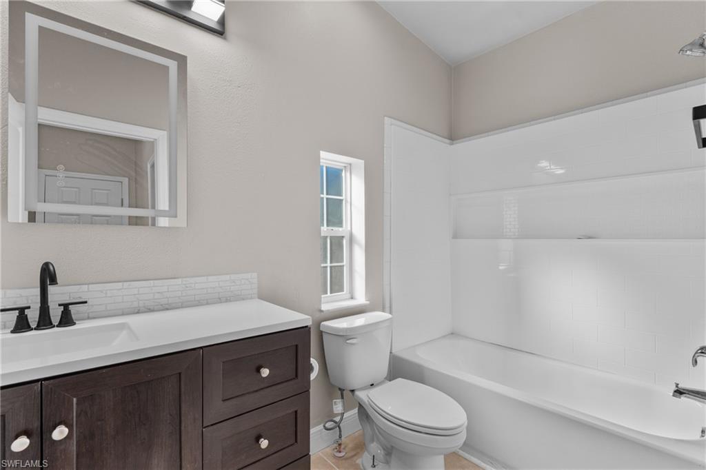 Full bath featuring vanity, bathtub / shower combination, and decorative backsplash