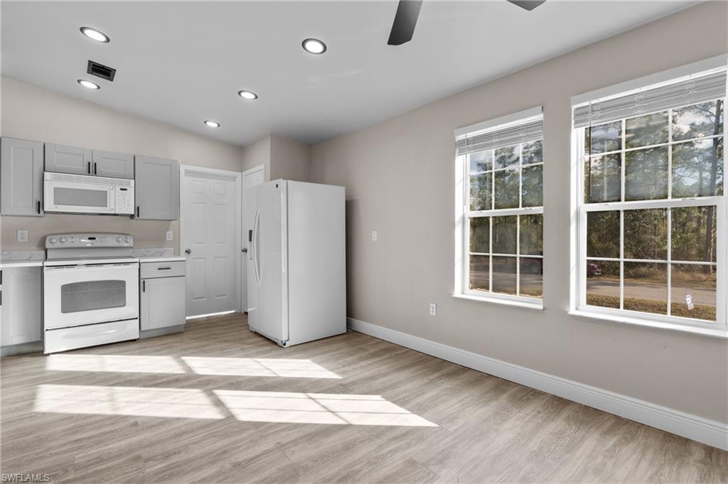 Kitchen featuring white appliances, light countertops, gray cabinetry, light wood-style floors, and recessed lighting