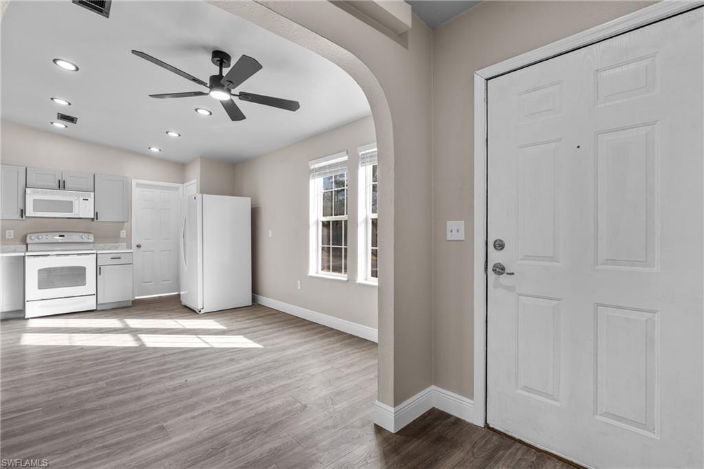 Kitchen featuring arched walkways, white appliances, light countertops, light wood-type flooring, and a ceiling fan