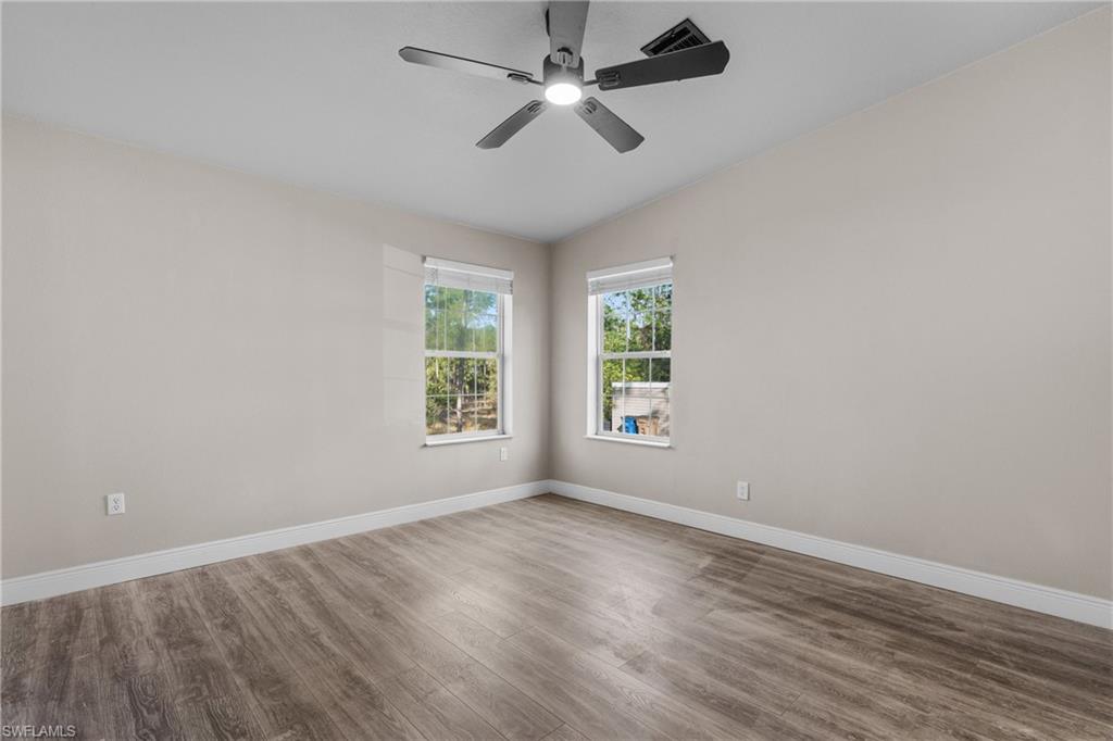 Spare room with wood finished floors, lofted ceiling, and a ceiling fan