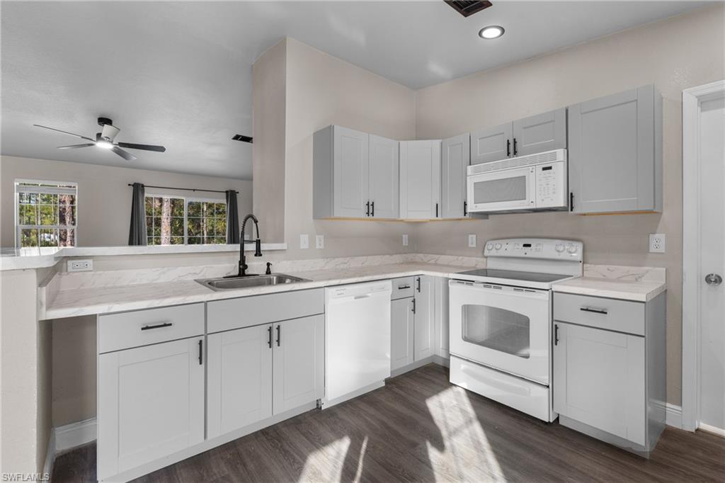 Kitchen with white appliances, light countertops, and dark wood-style floors