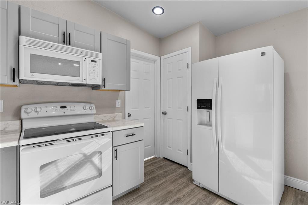 Kitchen with white appliances, light countertops, light wood-style floors, gray cabinetry, and recessed lighting