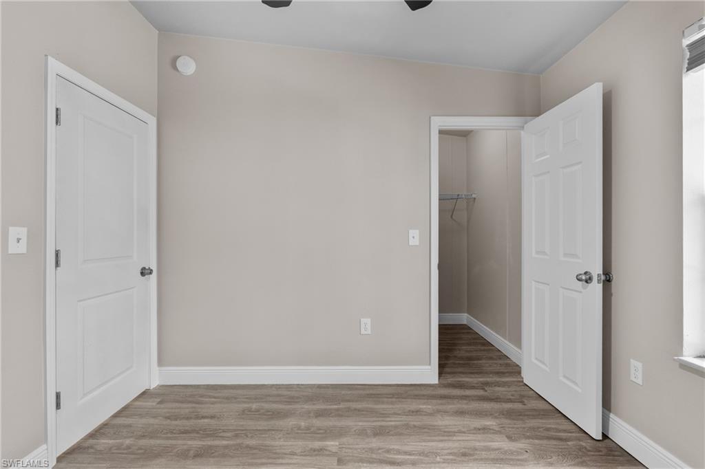 Unfurnished bedroom featuring a walk in closet, light wood-style flooring, and ceiling fan
