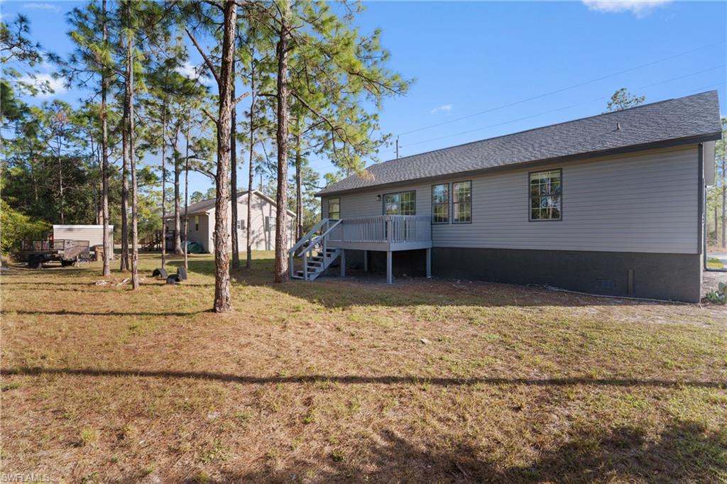 Rear view of property featuring a wooden deck, crawl space, a yard, and stairs