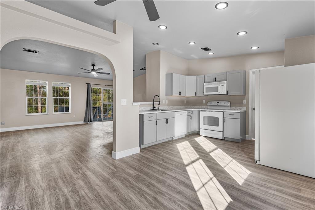 Kitchen with white appliances, light countertops, open floor plan, light wood-style flooring, and recessed lighting