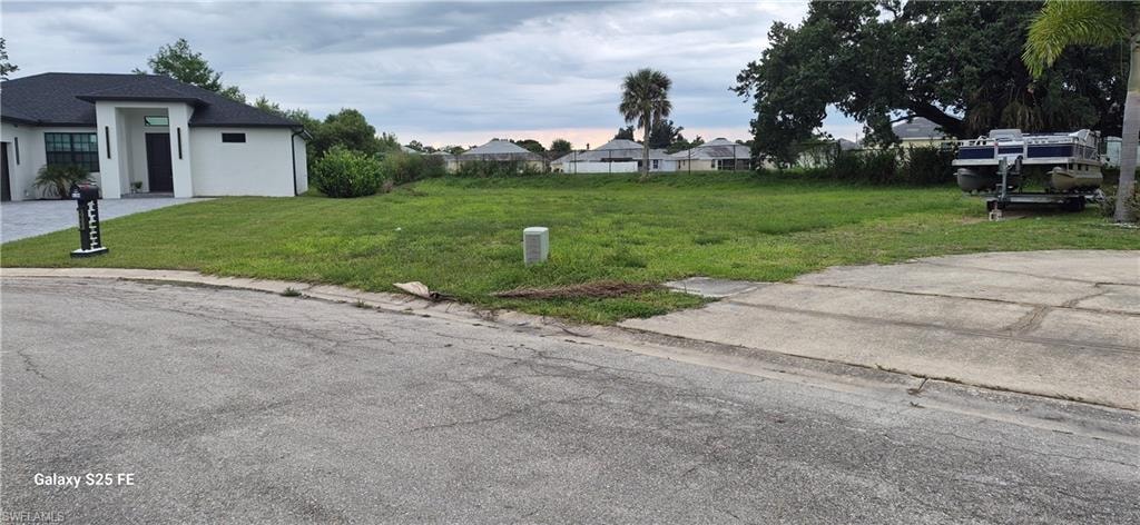 Expansive cleared lot with established grass, featuring existing curb cut for driveway access