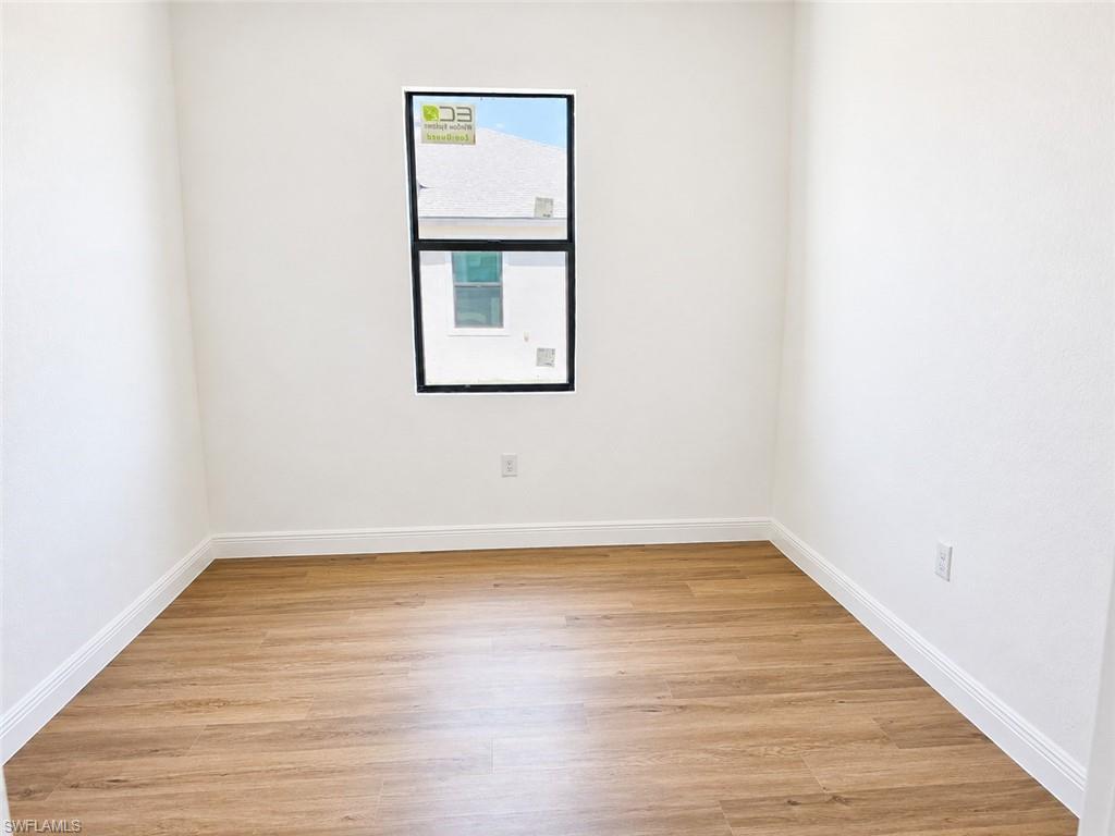 Neutral painted walls with wood-finish flooring and white baseboards