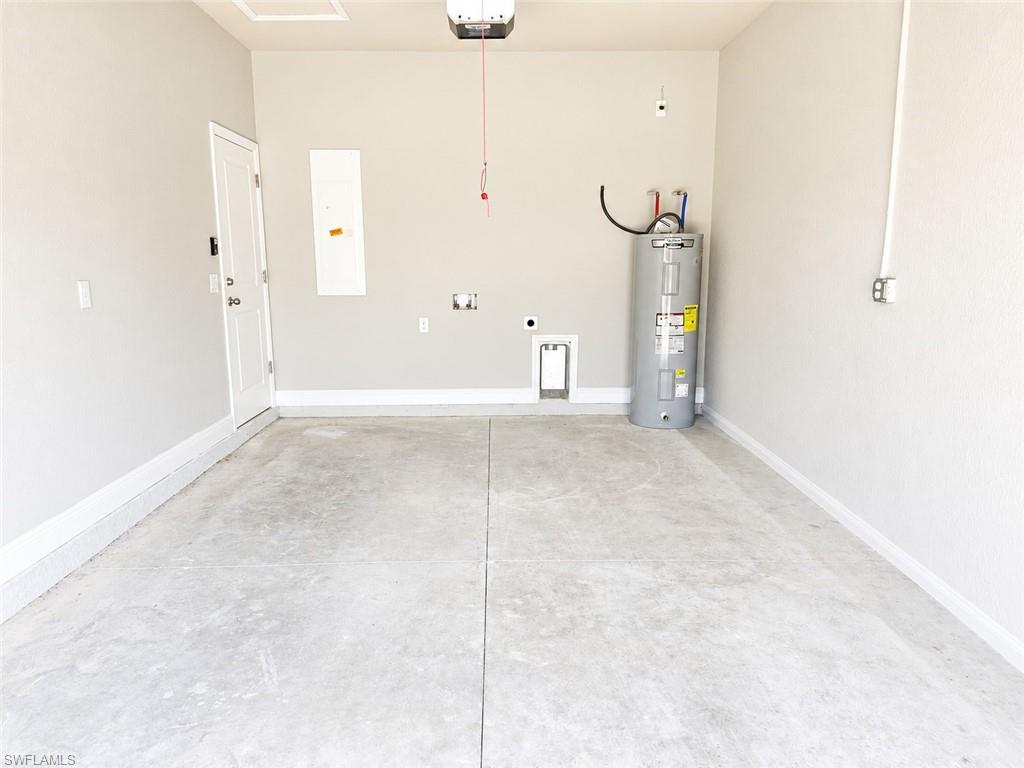 Spacious garage featuring a concrete floor, painted walls, white trim, and a water heater installation