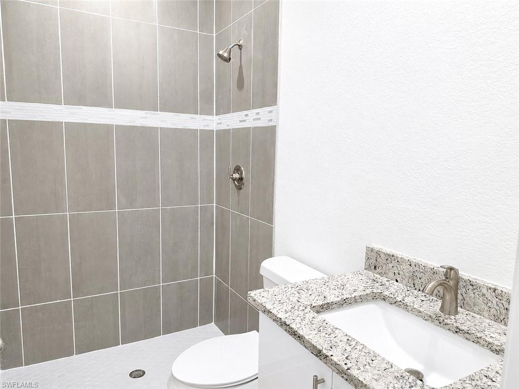 Master Bathroom featuring a shower with large format grey wall tiles and a decorative mosaic accent strip